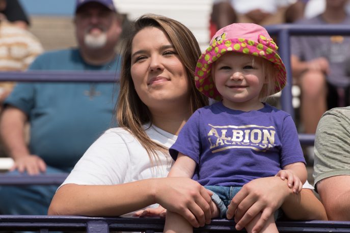 Child in the bleachers in an Albion Lacrosse shirt.