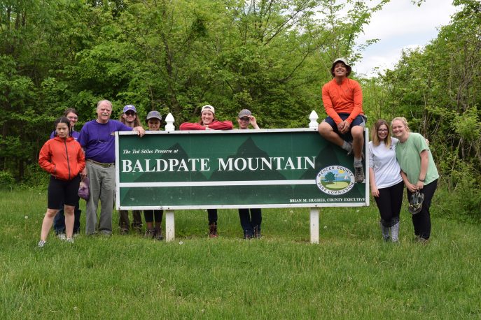 Group of students and faculty member posed with a sign reading 