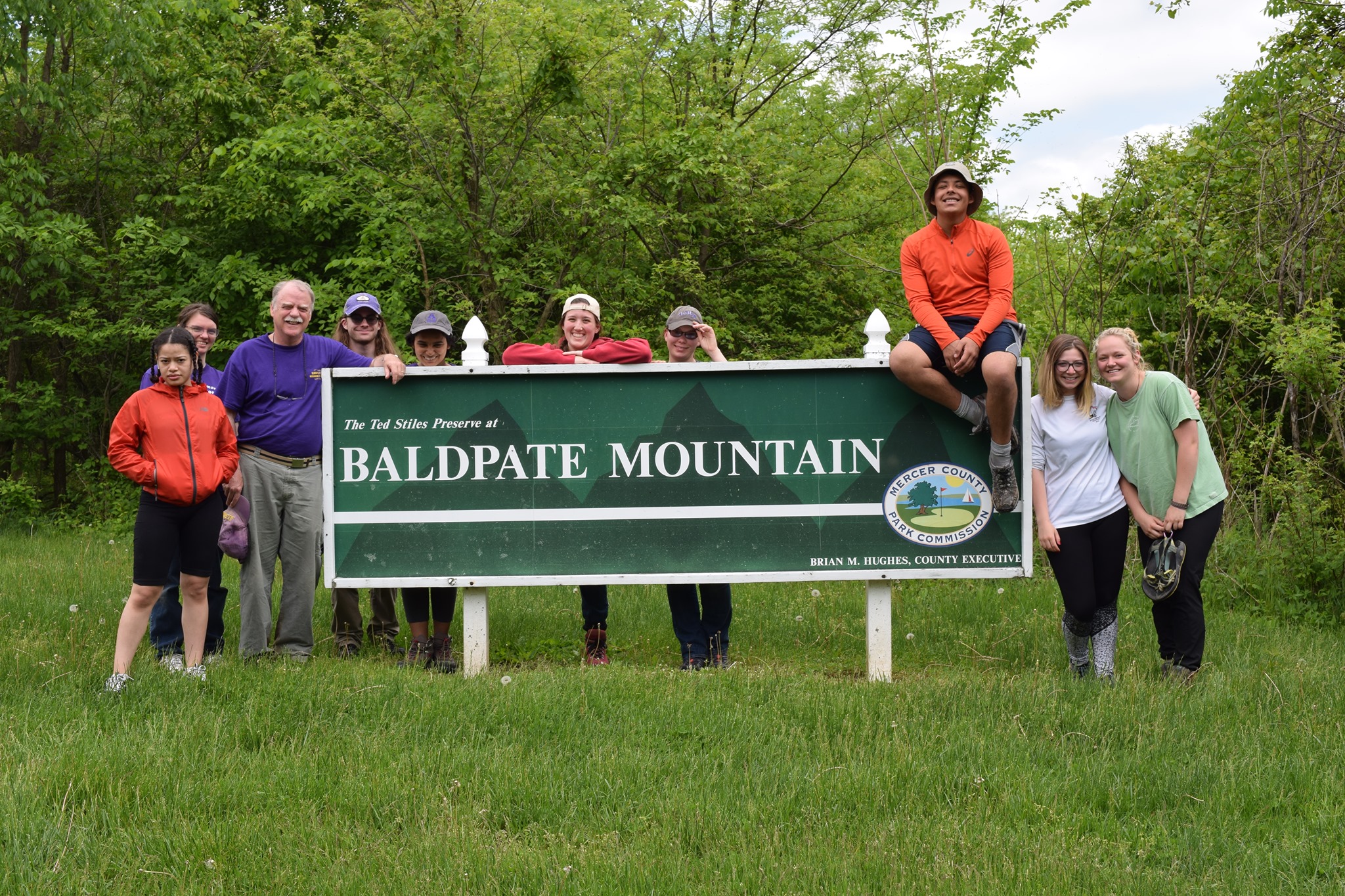 Group of students and faculty member posed with a sign reading 