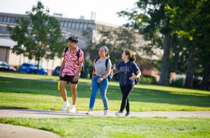 Three students walking outside on campus.
