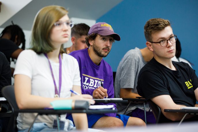Three students sitting in class, looking ahead to the professor.
