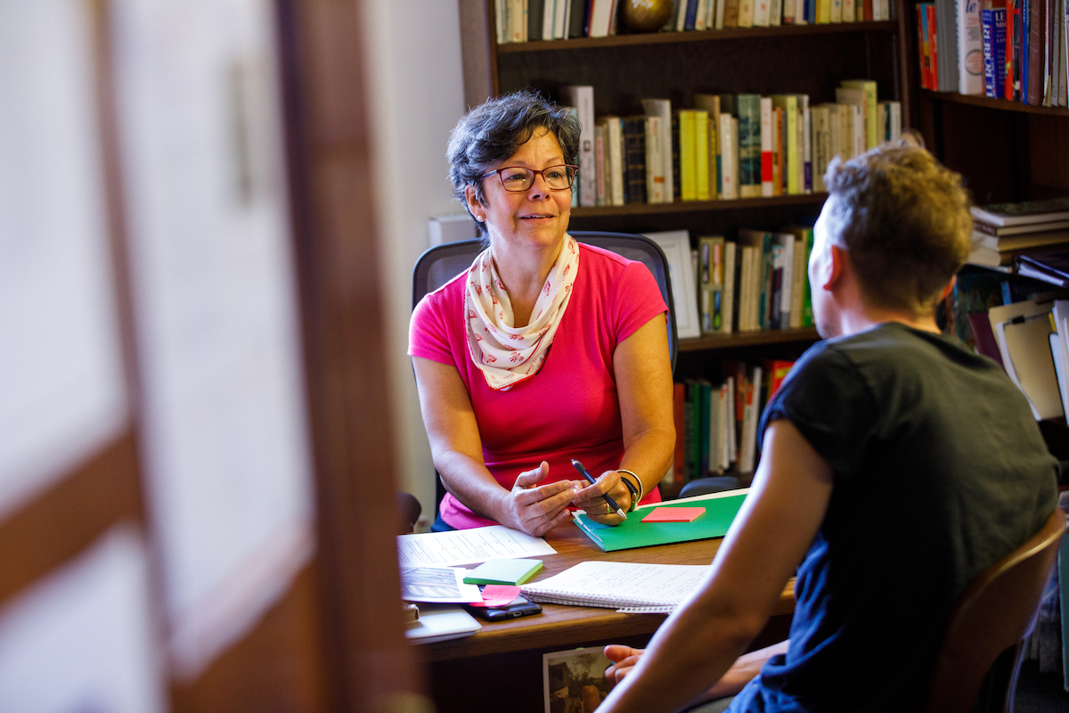 Faculty member speaking with a student in an office