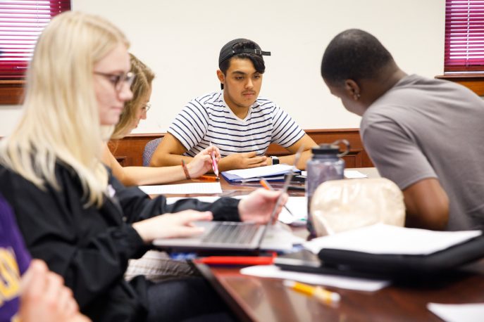 Albion students gathered around a table and working together.