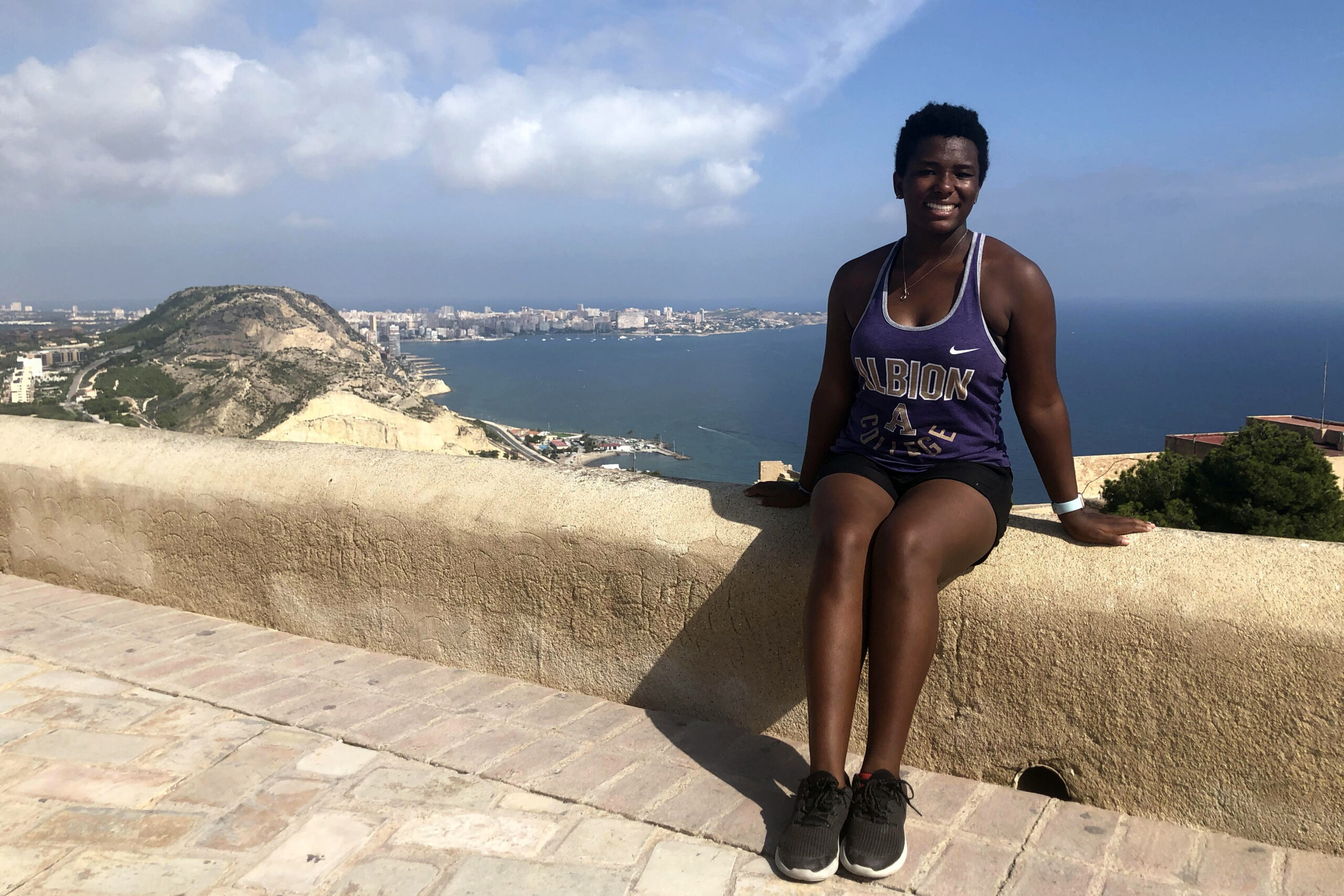 LaRhonda Richardson sitting on a coastal wall in front of the ocean in Spain.
