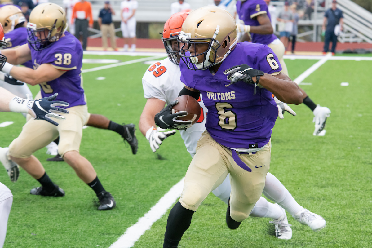 Member of the Albion College football team running with a football during a game.