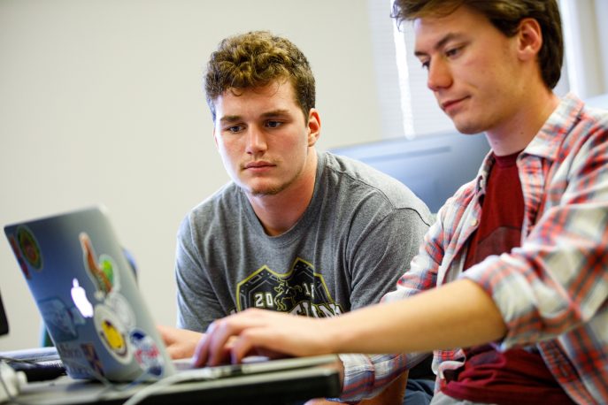 Two students working together on a laptop computer.