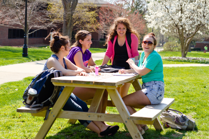 Four students working outside at a picnic table.