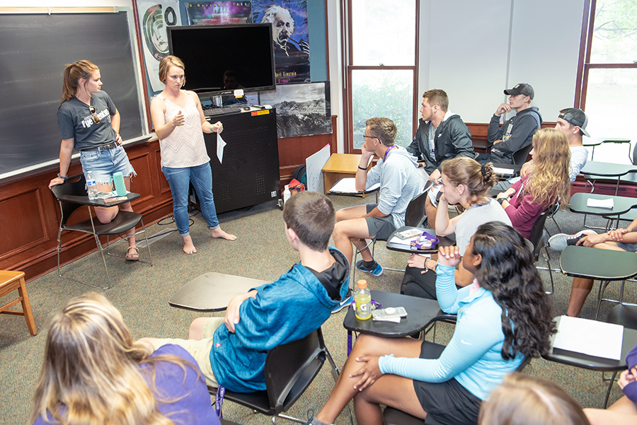 Two First-Year Experience Mentors address a classroom of students during move-in.