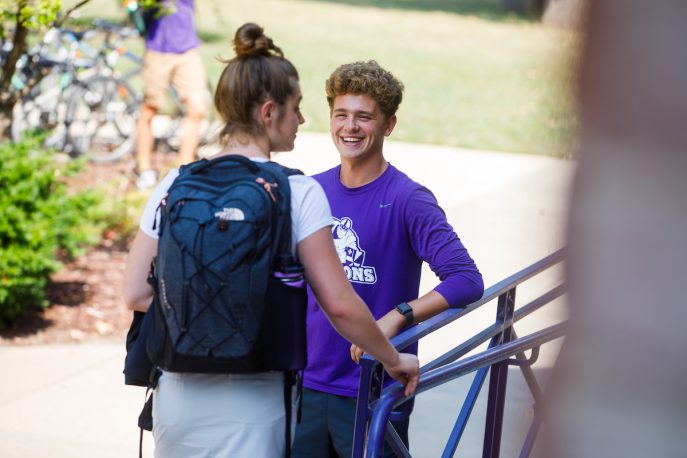 Two students in conversation on the steps of Kresge.