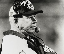 A man wearing a Green Bay Packers hat and head set.
