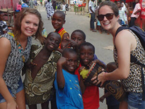 Two students posing with a group of children.