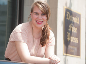 A student smiling in front of a building.