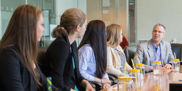 A row of students sitting at a table with a professor at the end.