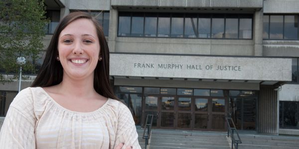 A smiling student in front of a building.