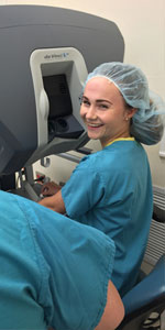 A student wearing scrubs looking over her shoulder.