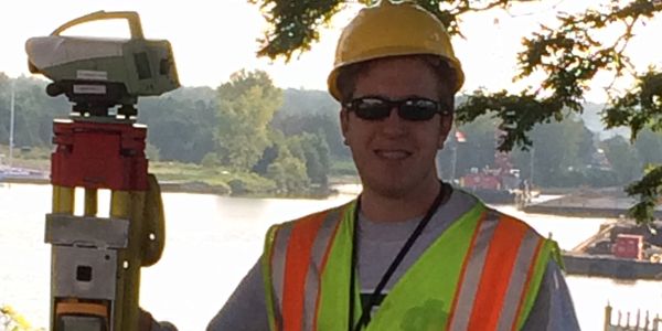 A student wearing a construction vest and hat.