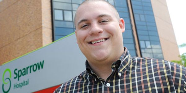A smiling student standing in front of a building.