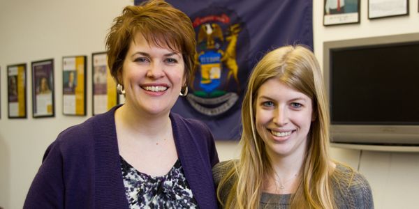 A student standing next to a woman.