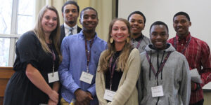 A group of students posing for the camera next to a window.