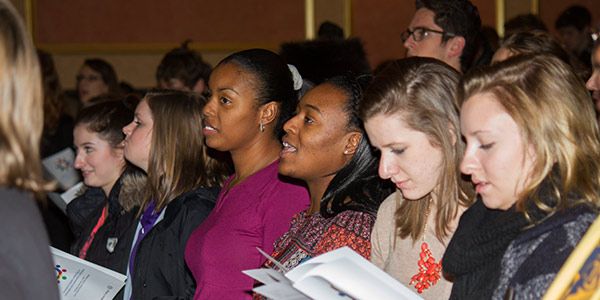 People standing in an auditorium singing.