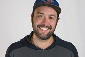 A man wearing a baseball cap smiling at the camera.