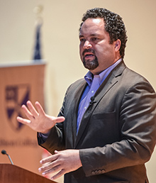 A person in a suit speaking and gesturing with their hands.