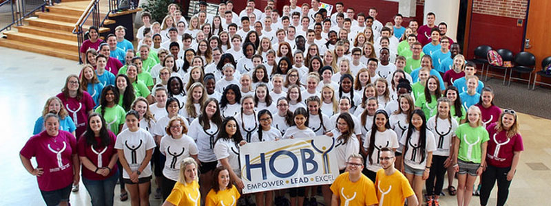 Large group of students holding summer camp sign