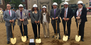 A group of people standing in a row with shovels.