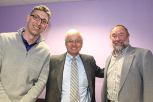 Three men smiling at the camera.