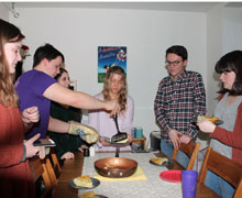 A group of students standing around a dinner table.