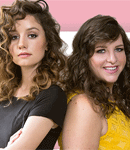 Two woman back to back smiling.