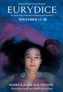 A woman in a pink dress laying back in a pool of water.