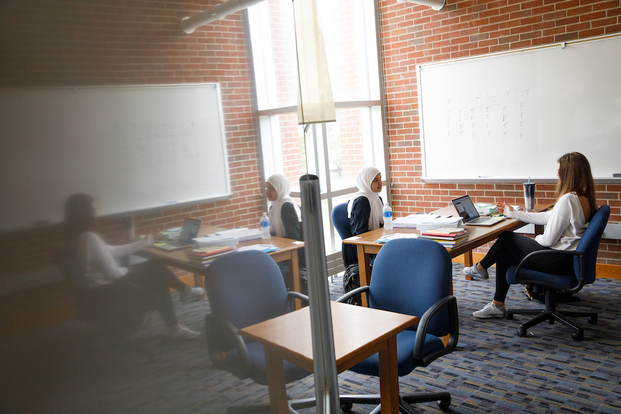 Two students in conversation next to a whiteboard.