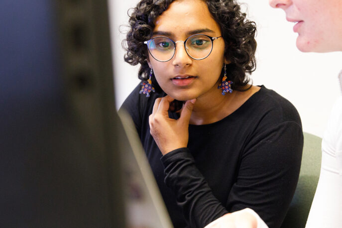 Two students working together on a desktop computer.