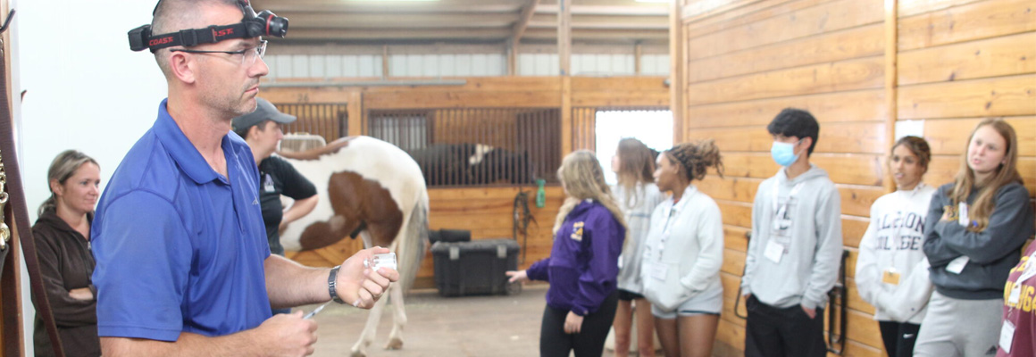 A veterinarian loads a syringe while lecturing to students.