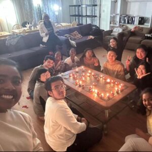Smiling students gathered around a coffee table with candles for Diwali