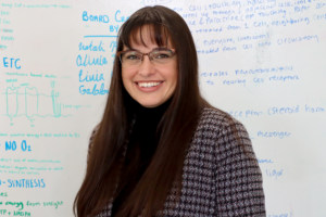 Jackie Gutierrez standing in front of a whiteboard in the Trio lab. 