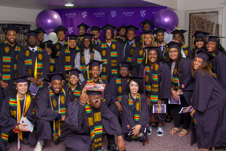 Graduating students wearing academic regalia pose together.