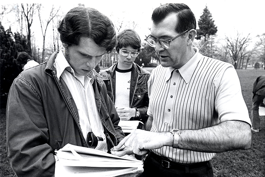 Dean Dillery teaches a student who sits in front of a microscope. 