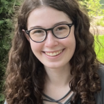 Caroline smiling with an outdoor scene in the background.